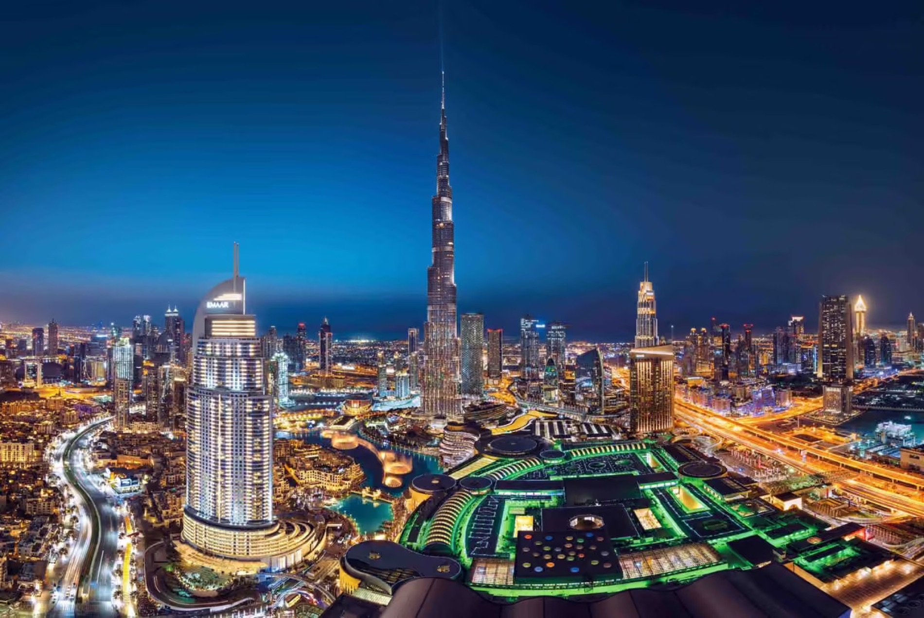 Downtown Dubai at dusk, the Burj Khalifa rising above the surrounding towers, with the city lit below.